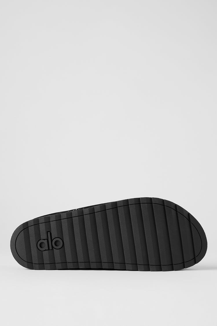 Alo Recovery Slipper in the black suede color with a faux fur lining.